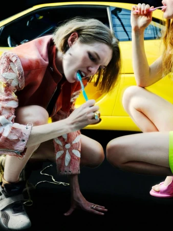 Model squatting in front of a yellow car while brushing teeth, photographed by Francesco Bonasia for King Kong Magazine