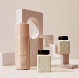 Product still life of three Kevin Murphy hair care bottles arranged against geometric pink and neutral studio props