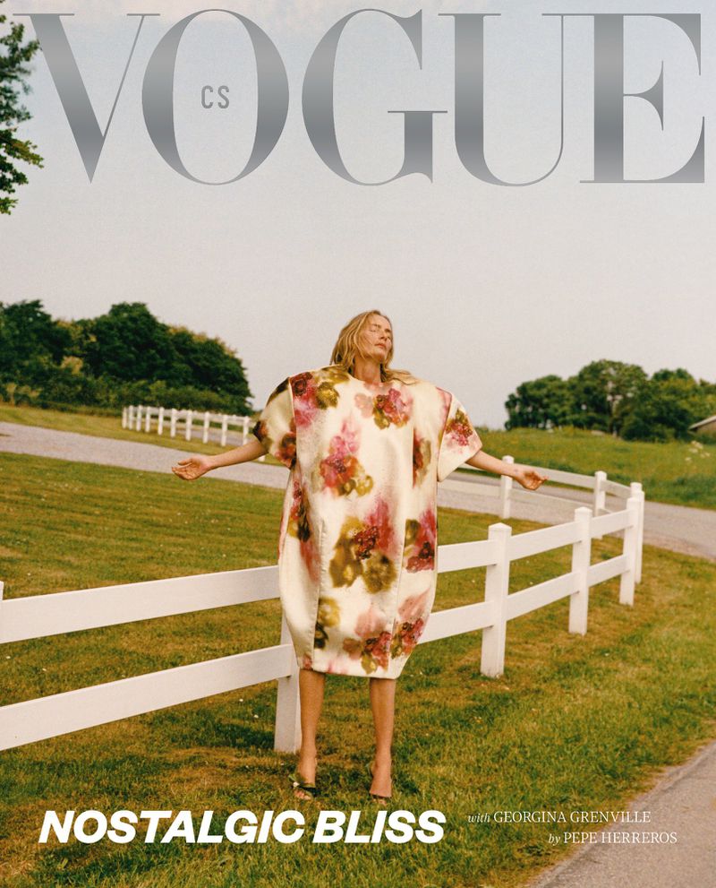 Model Georgina Grenville in a floral balloon dress with outstretched arms beside a white fence for Vogue Czechoslovakia.