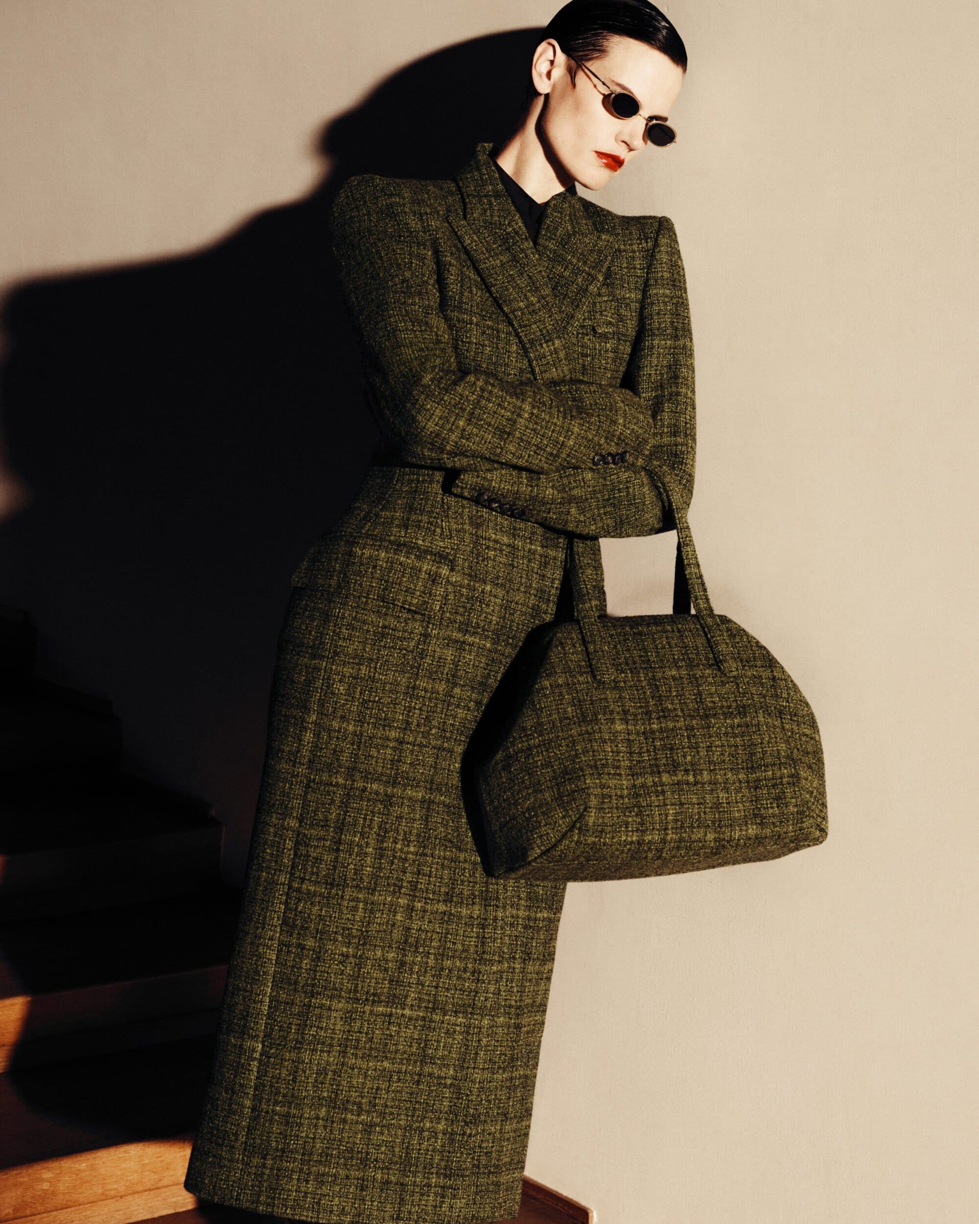 Saskia de Brauw wearing a tailored olive green tweed coat with matching handbag and dark sunglasses for Mugler.