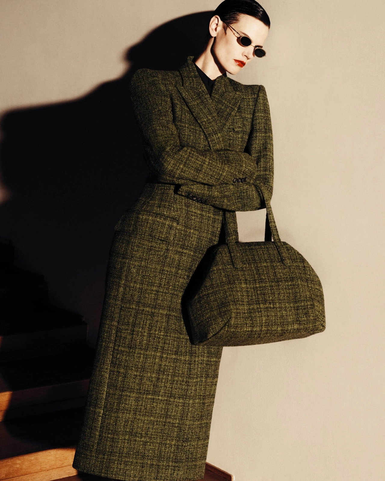 Saskia de Brauw wearing a tailored olive green tweed coat with matching handbag and dark sunglasses for Mugler.