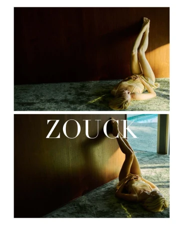 Model India Tuersley in a pale slip dress lying on carpet with legs raised against a wooden wall in Hans Neumann's Zouck.