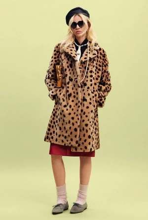 Model in a leopard print coat, black beret, and sunglasses posing against a pale green backdrop.