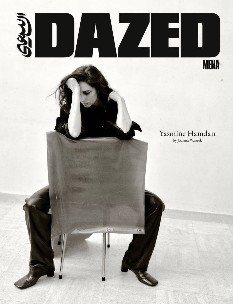 Black and white magazine cover featuring singer Yasmine Hamdan seated backwards on a chair against a plain wall.