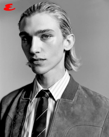 Black and white portrait of a young adult male with light skin, wearing a jacket, dress shirt, and tie, looking at the camera.
