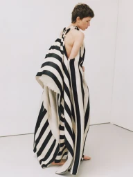 Model Nora Svenson posing in a sculptural black and white striped draped dress in a white studio for Vogue Ukraine.