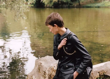 Model with short brown hair wearing a black leather jacket by a lake in a fashion editorial for Vogue Ukraine