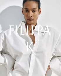 Model wearing a white button-down shirt against a minimal pale background for Filippa K