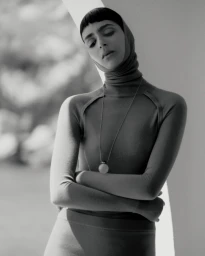 Model Nora Attal posing with arms crossed wearing a fitted turtleneck and long necklace for Vogue Greece Simple Narratives editorial.