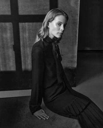 Monochrome portrait of model Anouk Smits seated on the floor in a long black pleated dress for Giada FW Pre Fall.