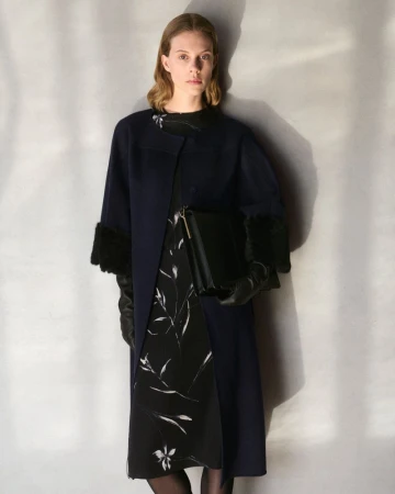 Model Anouk Smits wearing a navy blue coat with fur cuffs and floral printed dress for Giada FW Pre Fall collection.