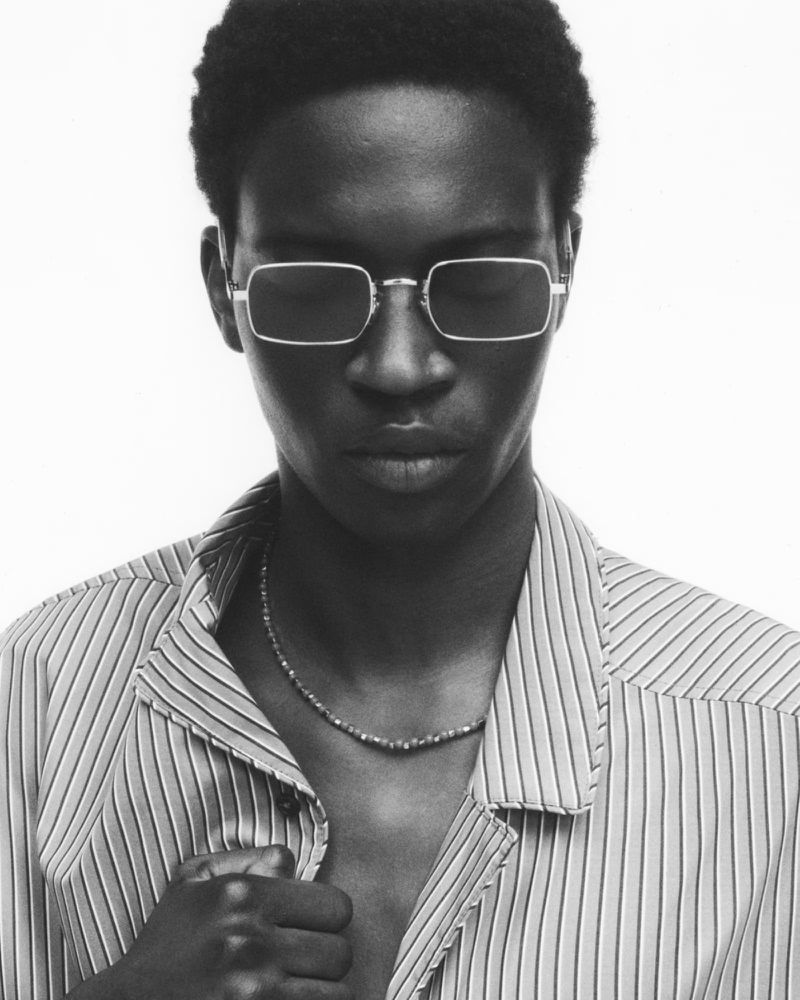 Portrait of a man wearing rectangular wireframe glasses and a striped shirt against a plain white background.