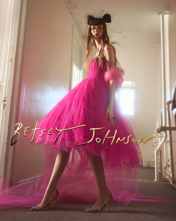 Sara Grace Wallerstedt wearing a vibrant pink tulle gown and floral heels with a black veiled headpiece.