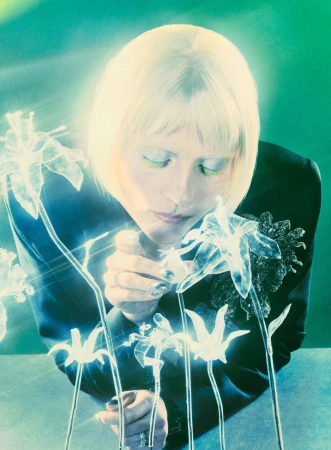 Mala Emde looking down at glowing glass flower sculptures wearing a black blazer for Vogue Germany.