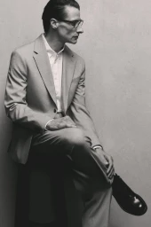 Model Jonas Mason seated wearing a grey suit and glasses for Zara Suits Collection, photographed by Santi de Hita.