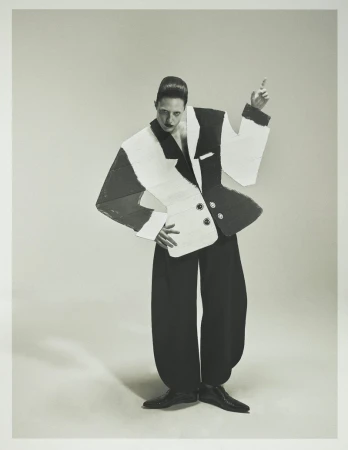 Model Julia Banas wearing an avant-garde geometric black and white cutout suit against a light grey studio background.
