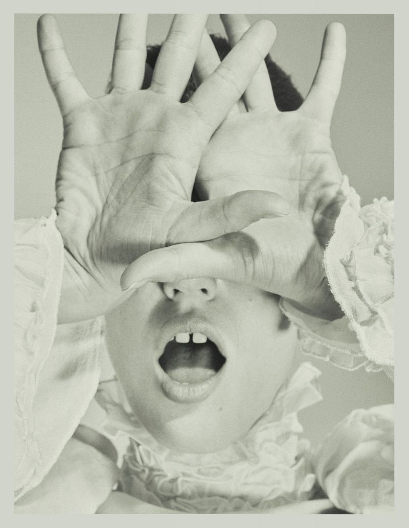 Julia Banas posing with open palms covering her eyes and mouth open wearing a white ruffled collar.