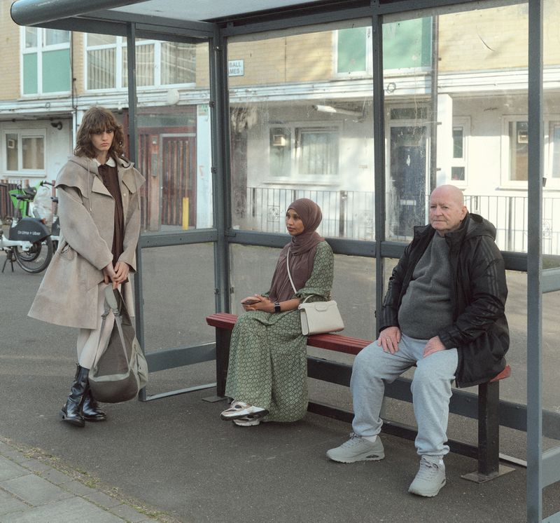 Model Katherine Vinten standing in a bus shelter alongside seated commuters for Albion Magazine editorial.