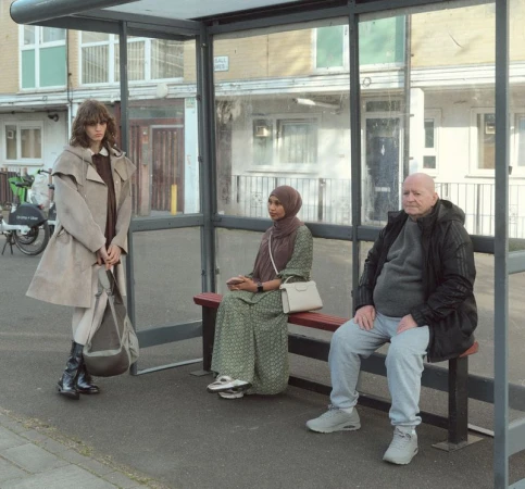 Model Katherine Vinten standing in a bus shelter alongside seated commuters for Albion Magazine editorial.