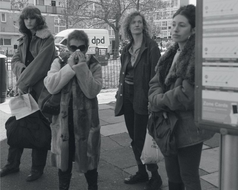 Black and white editorial image of four women waiting at a bus stop for Albion Magazine