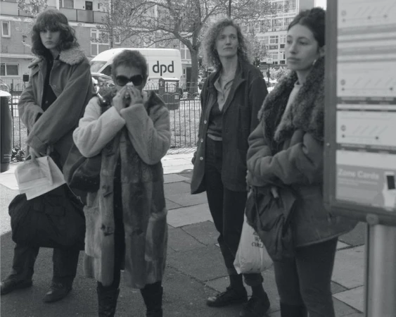 Black and white editorial image of four women waiting at a bus stop for Albion Magazine