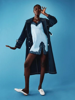 Model in pale blue slip dress and dark coat posing against solid blue backdrop for Vivetta Resort 2026.