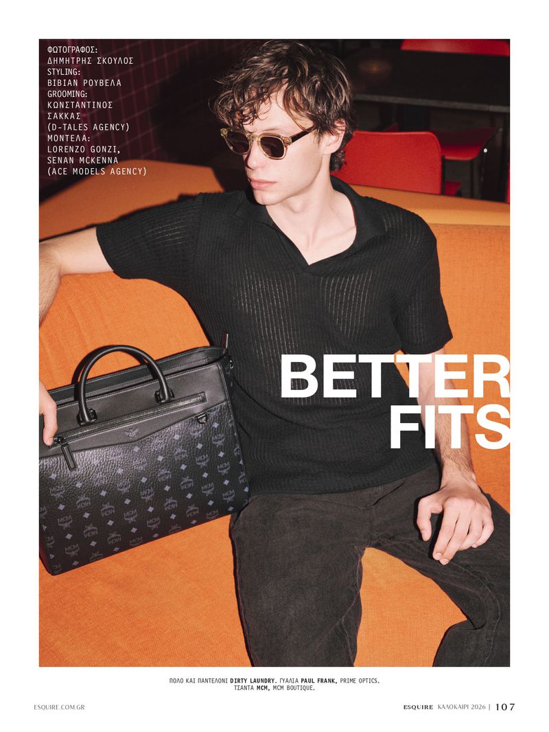 Model Lorenzo Gonzi wearing sunglasses and a black polo shirt seated on an orange sofa with a black patterned handbag, for Esquire Greece.