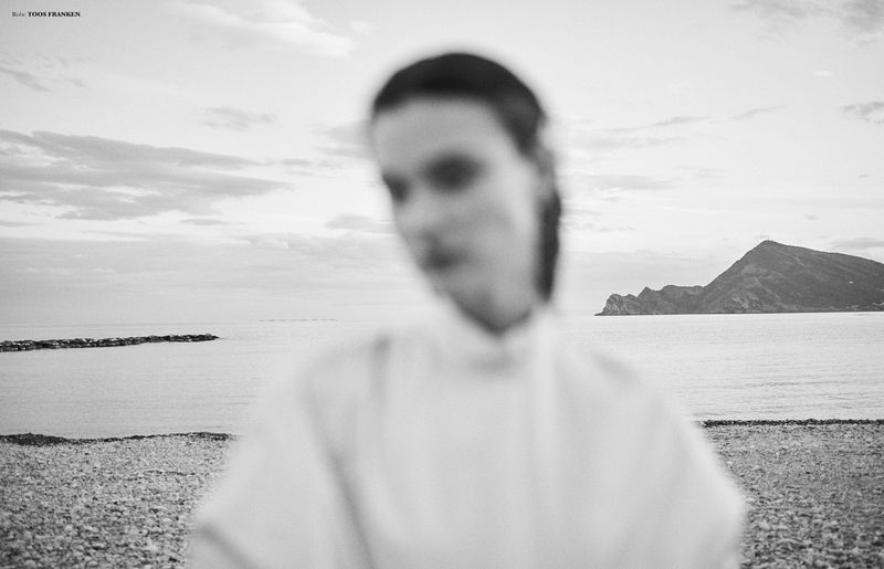 Black and white fashion editorial image of a model by the sea for Knack Weekend S/S 26, photographed by Hicham Riad.