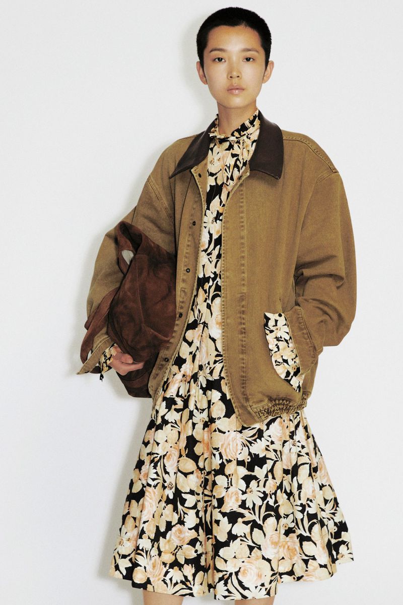 Model Echo Zhao posing in an oversized tan canvas jacket over a floral print dress against a white studio background.