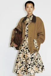 Model Echo Zhao posing in an oversized tan canvas jacket over a floral print dress against a white studio background.