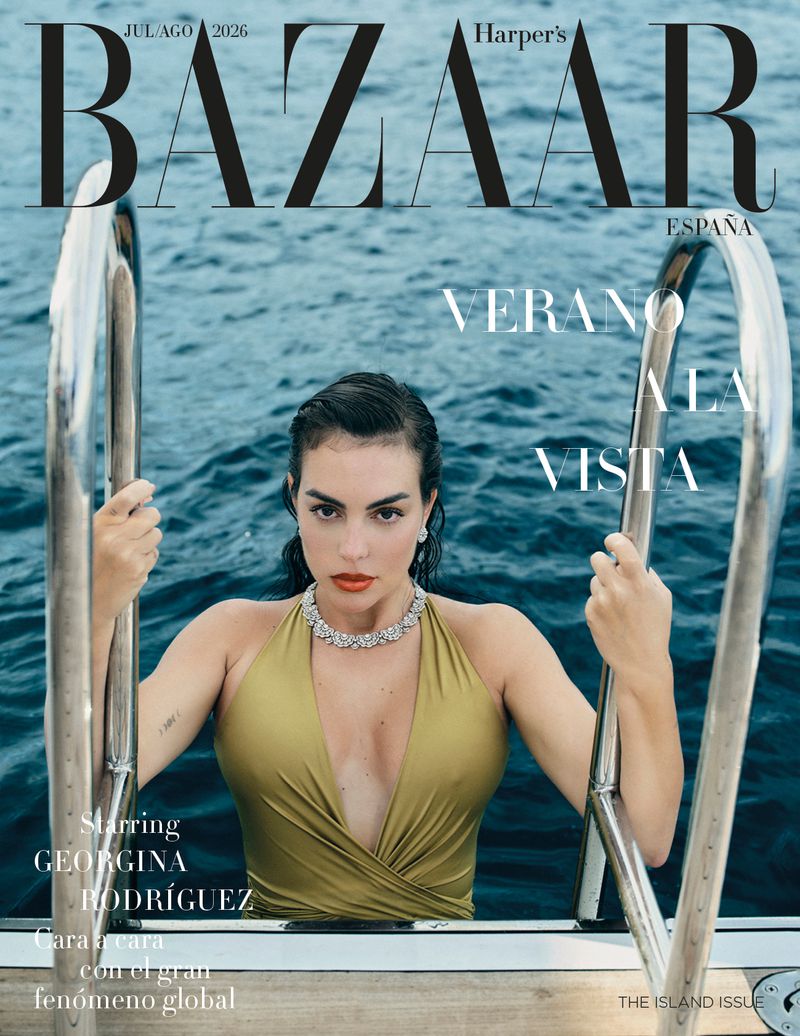 Georgina Rodríguez posing on a boat ladder in deep blue ocean water in an olive halter swimsuit for Harper's Bazaar España.