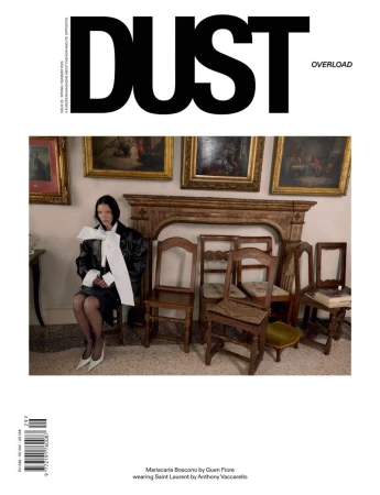 Mariacarla Boscono seated in an interior with wooden chairs and framed artwork for Dust Magazine