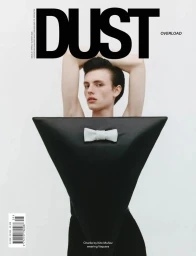 Model Charlie Jones on a magazine cover wearing a black inverted triangle garment with a white bow tie against a white background.