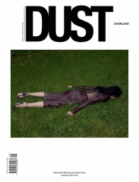 Dust Magazine cover featuring Mariacarla Boscono lying face down on a green grass lawn in a dark burgundy dress and heels.