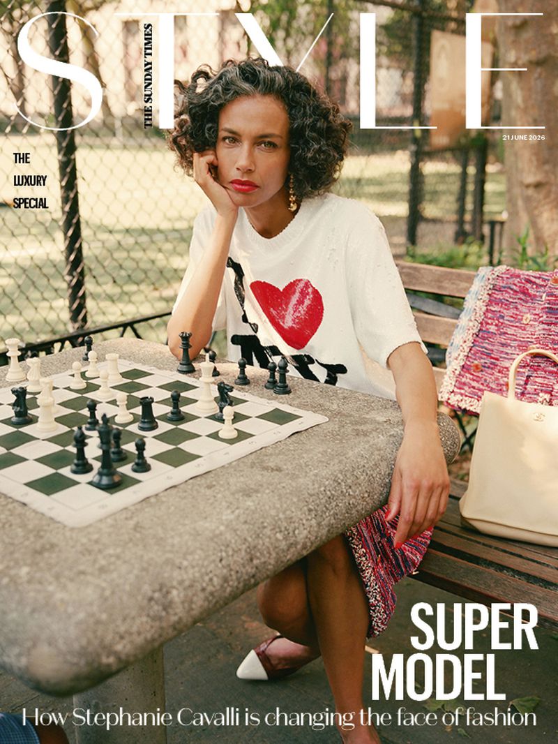 Model Stephanie Cavalli seated at an outdoor stone chess table wearing a white graphic t-shirt for The Sunday Times Style.