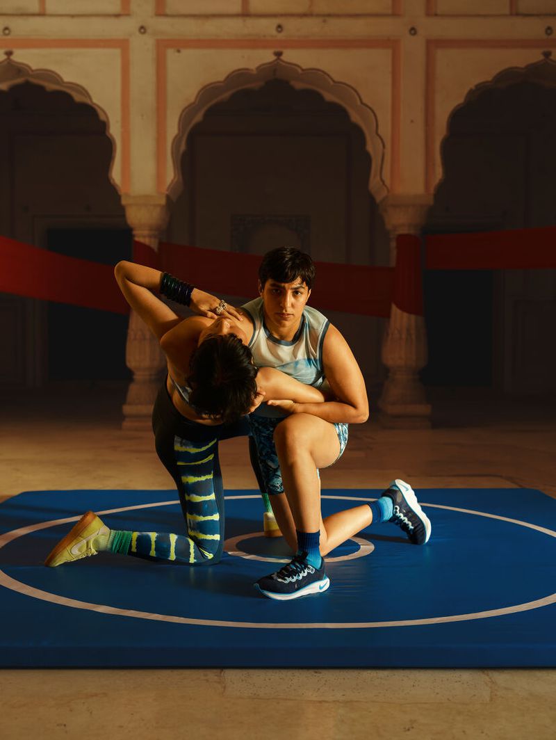 Two wrestlers compete on a blue mat indoors, showcasing athleticism, strength, and competitive spirit in a classic wrestling match.