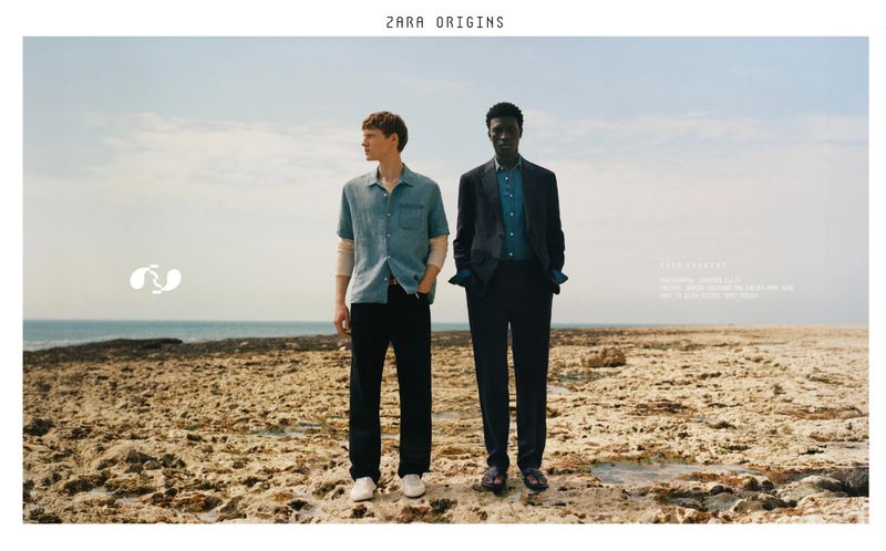 Two male models standing on a rocky coast by the ocean under an overcast sky for the Zara Origins campaign.
