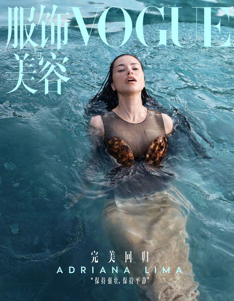 Fashion magazine cover featuring a woman partially submerged in water, wearing a sheer top with decorative accents in a close-up shot.