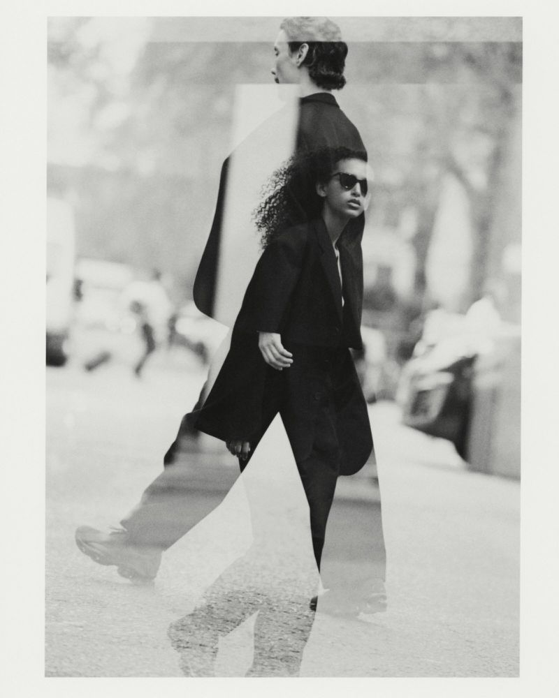 Monochrome multiple exposure image featuring two models wearing dark jackets walking outdoors on a city street