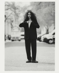 Model Tsion Teferi posing in a black oversized tailored suit on an urban street in black and white.