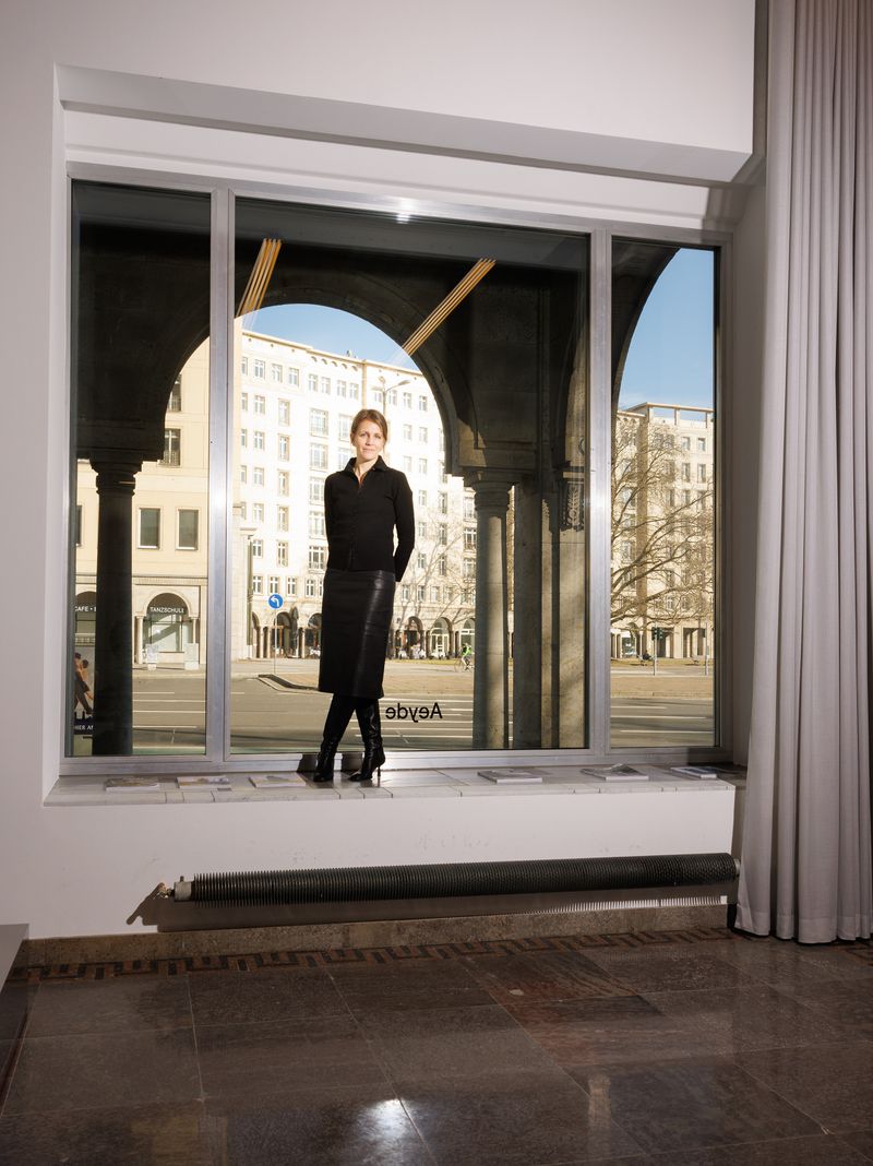 Luisa Dames standing on a window ledge wearing a black long-sleeve top, leather pencil skirt, and black boots.