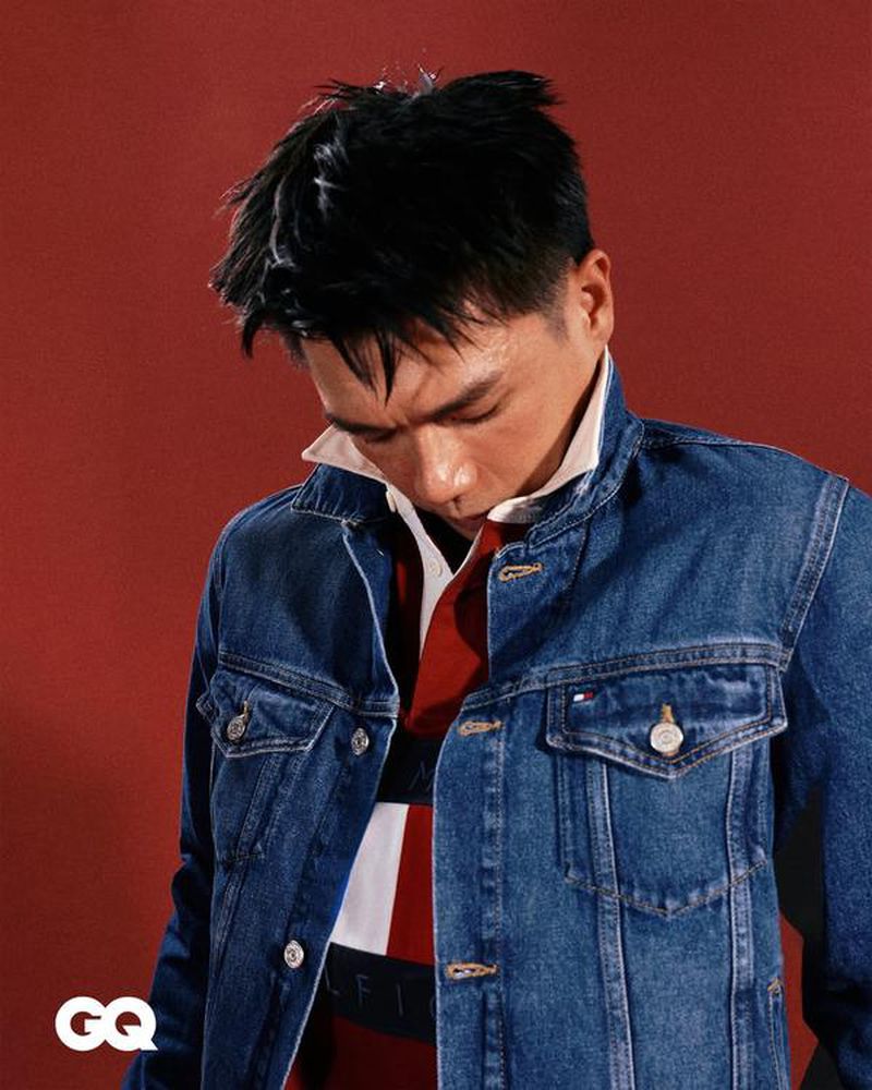 Man wearing a blue denim jacket over a color-blocked polo shirt against a red background for GQ Hong Kong