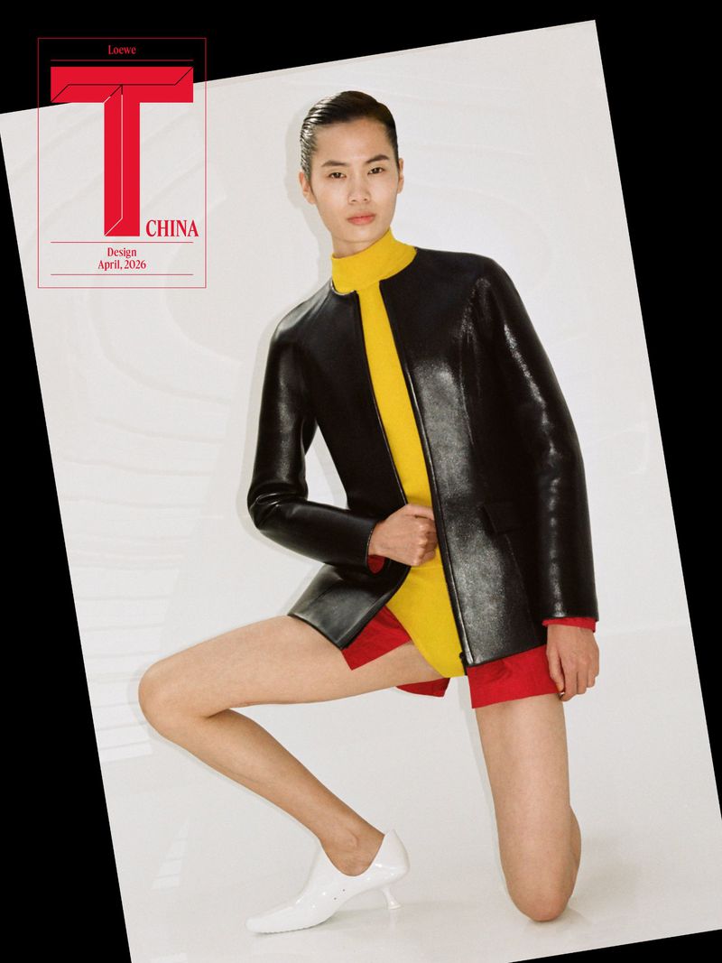 Model kneeling wearing a black leather jacket over yellow top and white shoes against a white backdrop