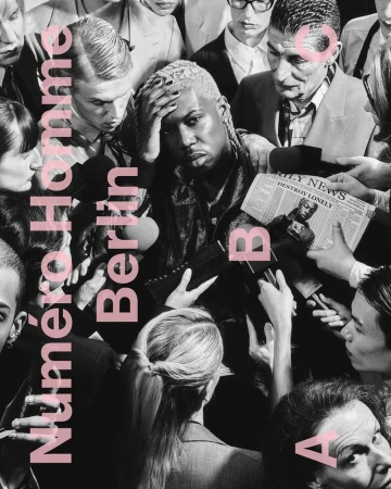 Editorial fashion shot of a man surrounded by people holding microphones and newspapers, with pink text overlay on a monochrome image.
