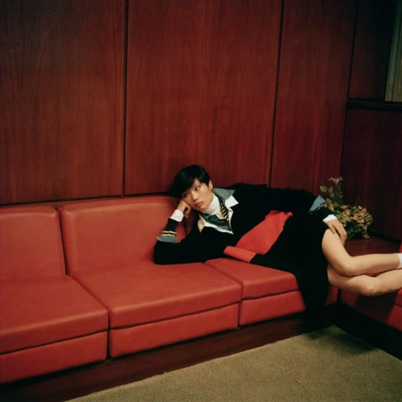 Model Kayako lounging across a red leather sofa against dark wood-paneled walls in an editorial for Harper's Bazaar France.