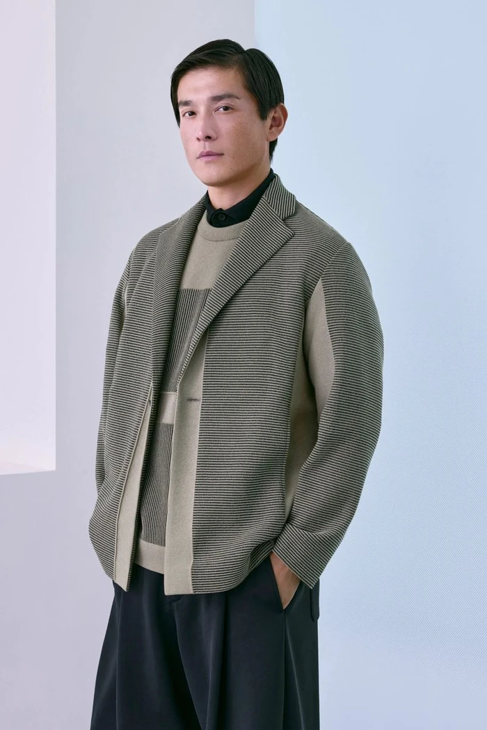 Daisuke Ueda wearing a textured sage green knit jacket layered over a knit sweater and dark trousers for CFCL Men's Lookbook.
