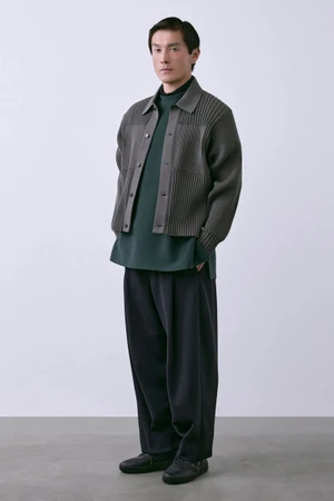 Model Daisuke Ueda in a grey ribbed knit jacket, deep green shirt, and wide-leg trousers for CFCL S/S 27 Men's Lookbook.
