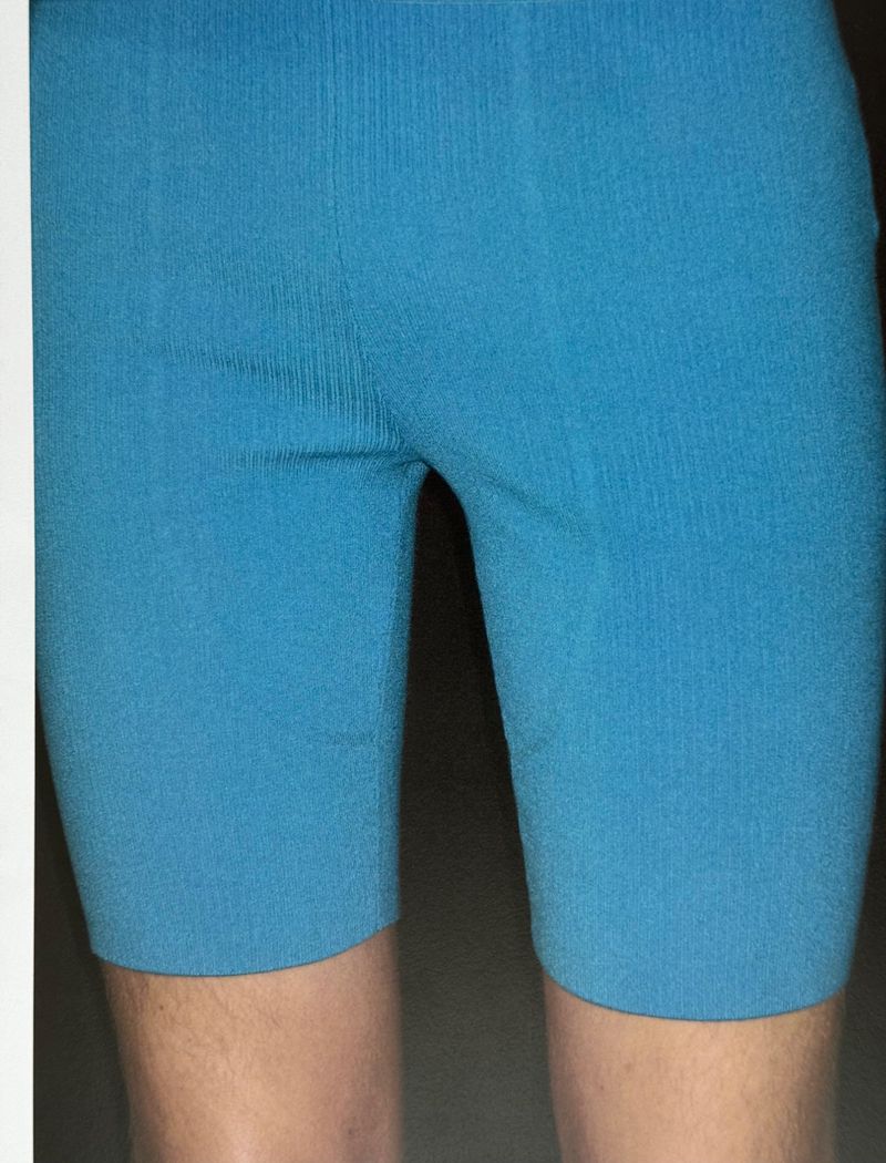 Close-up of a person wearing bright cyan athletic compression shorts, highlighting the texture and fit of the activewear.