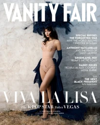 Lisa wearing a nude sculpted bodysuit, navy cape, and dramatic feathered headdress on the cover of Vanity Fair.