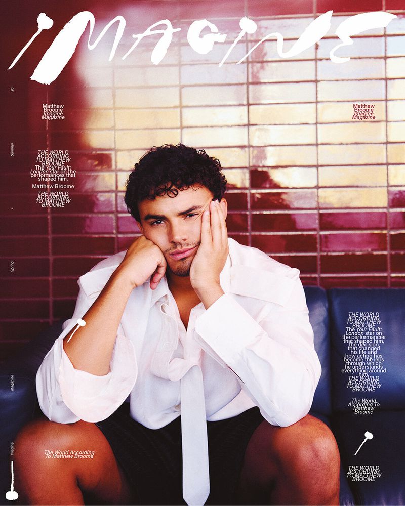 Actor Matthew Broome resting his face on his hand while seated on a blue sofa against a red tiled wall for IMAGINE Magazine.